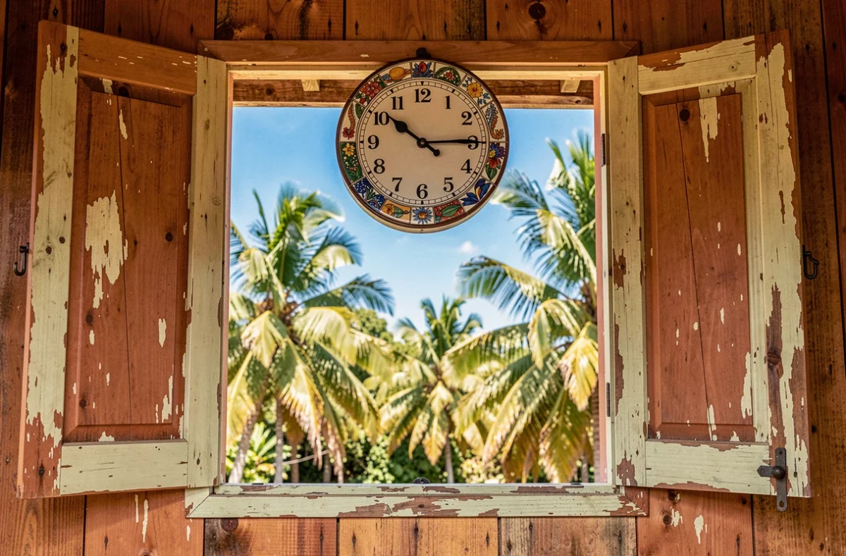 Horloge murale dans une maison créole traditionnelle en Guadeloupe avec vue sur les palmiers